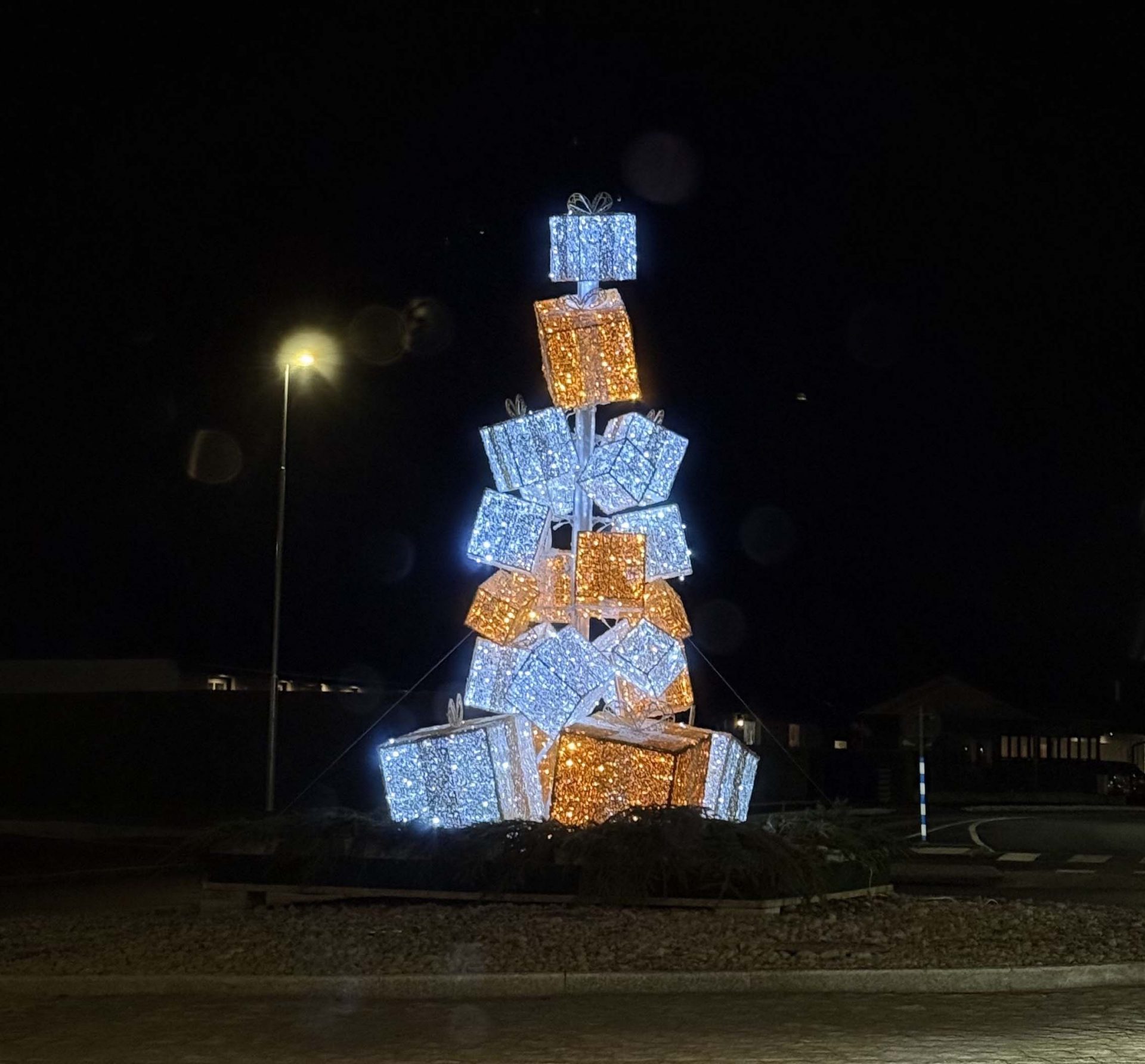 A stack of lit up gifts in the shape of a tree- it is the holidays.