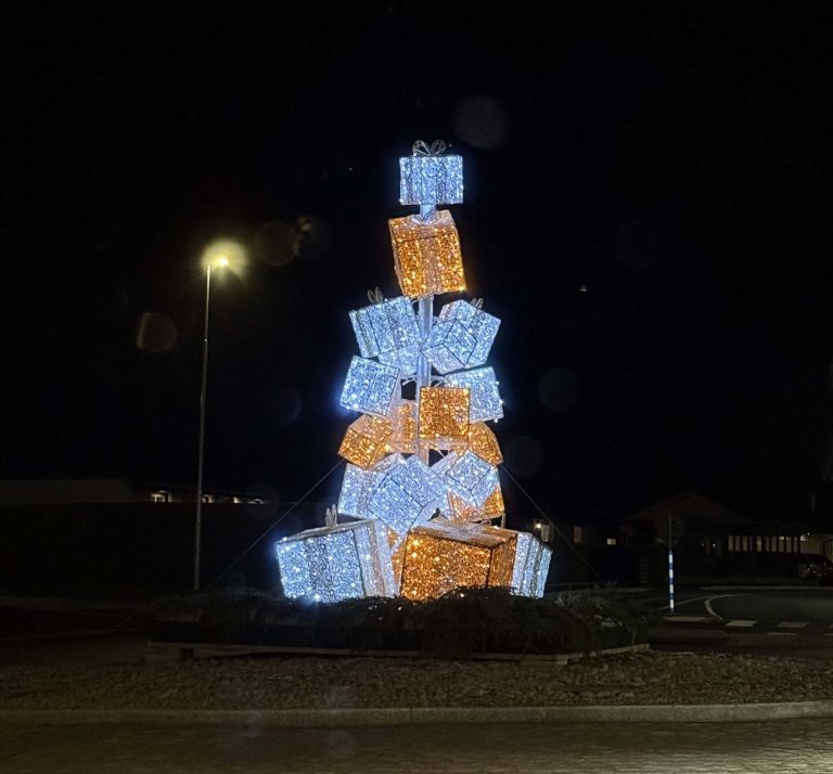 A stack of lit up gifts in the shape of a tree- it is the holidays.