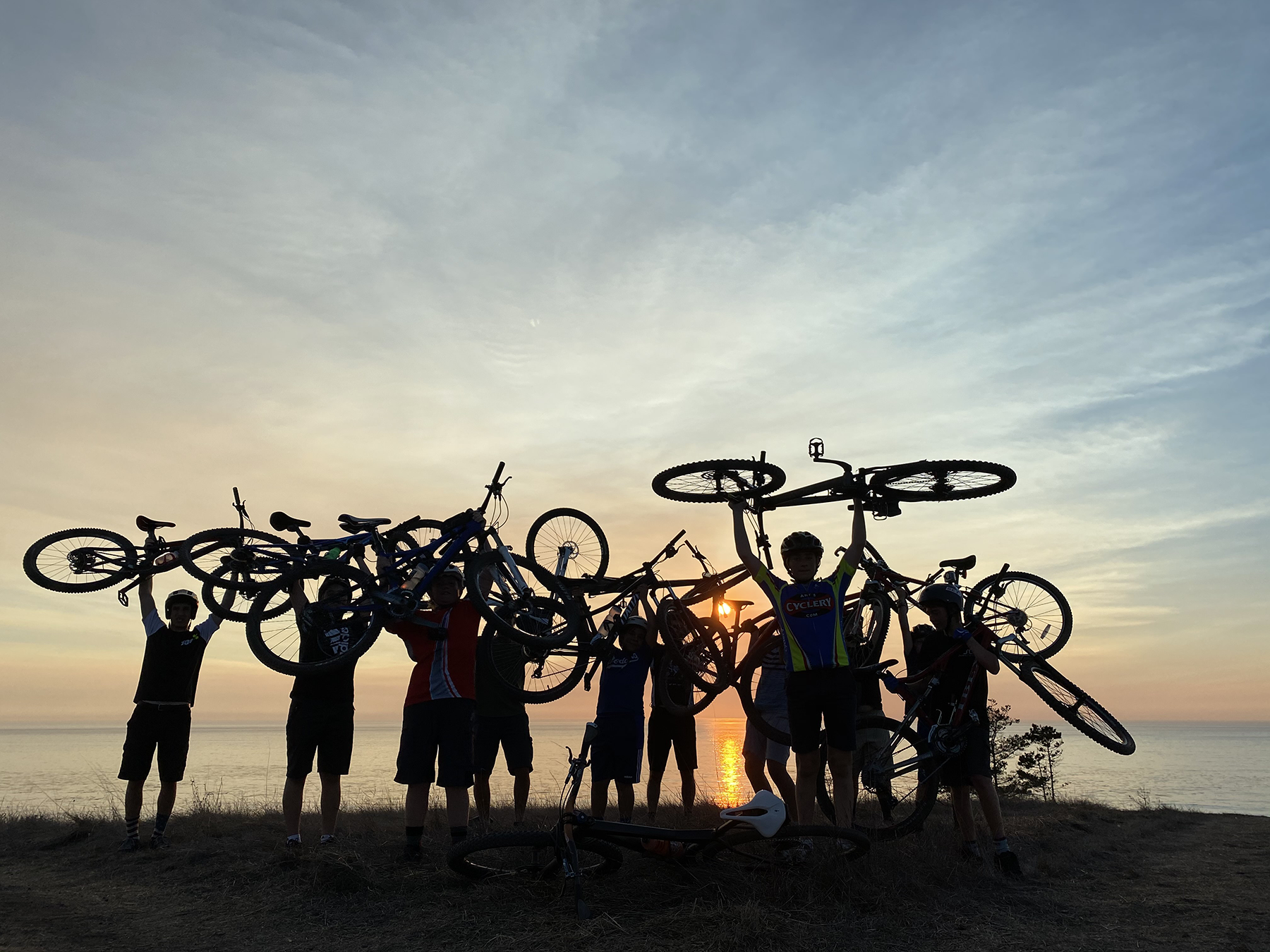Group of mountain bikers holding up their bikes.